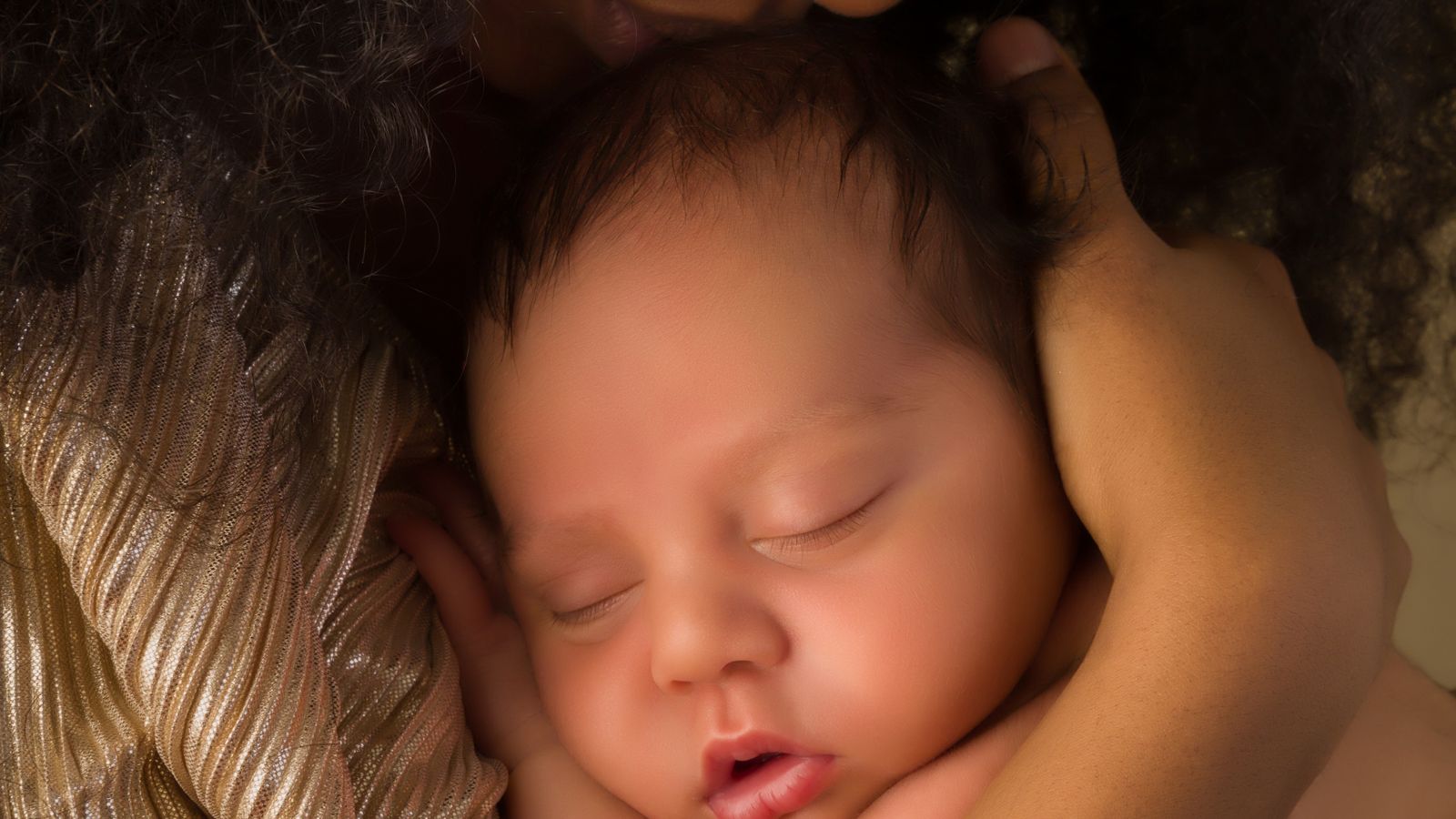 A peaceful sleeping newborn cradled in loving hands