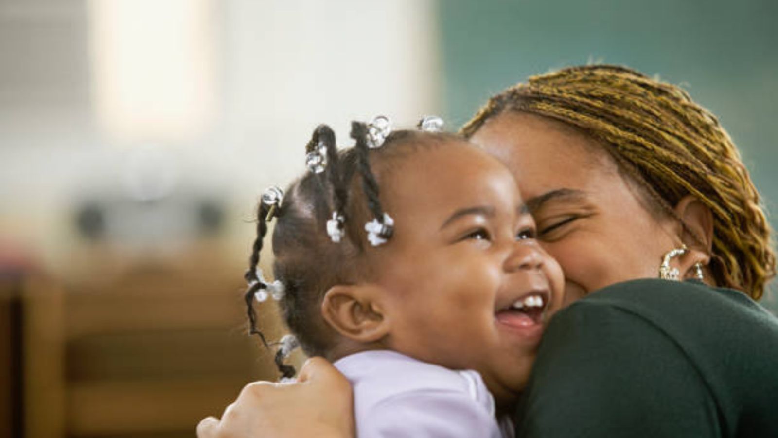 A laughing toddler hugging her mother