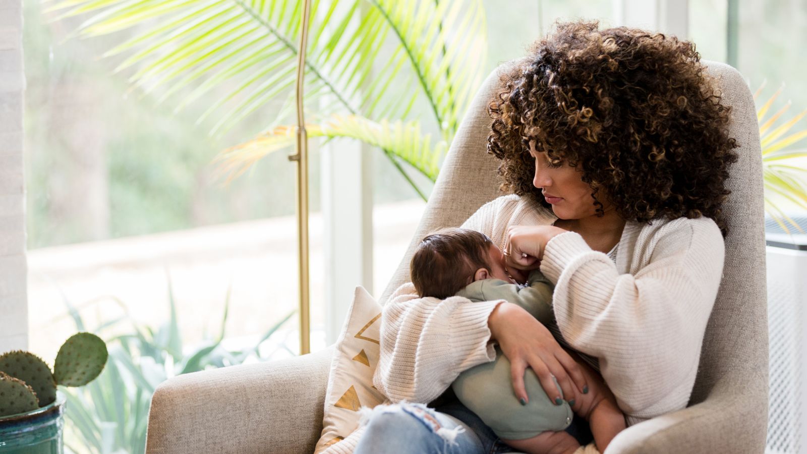 A mother feeding her baby in a sunlit armchair
