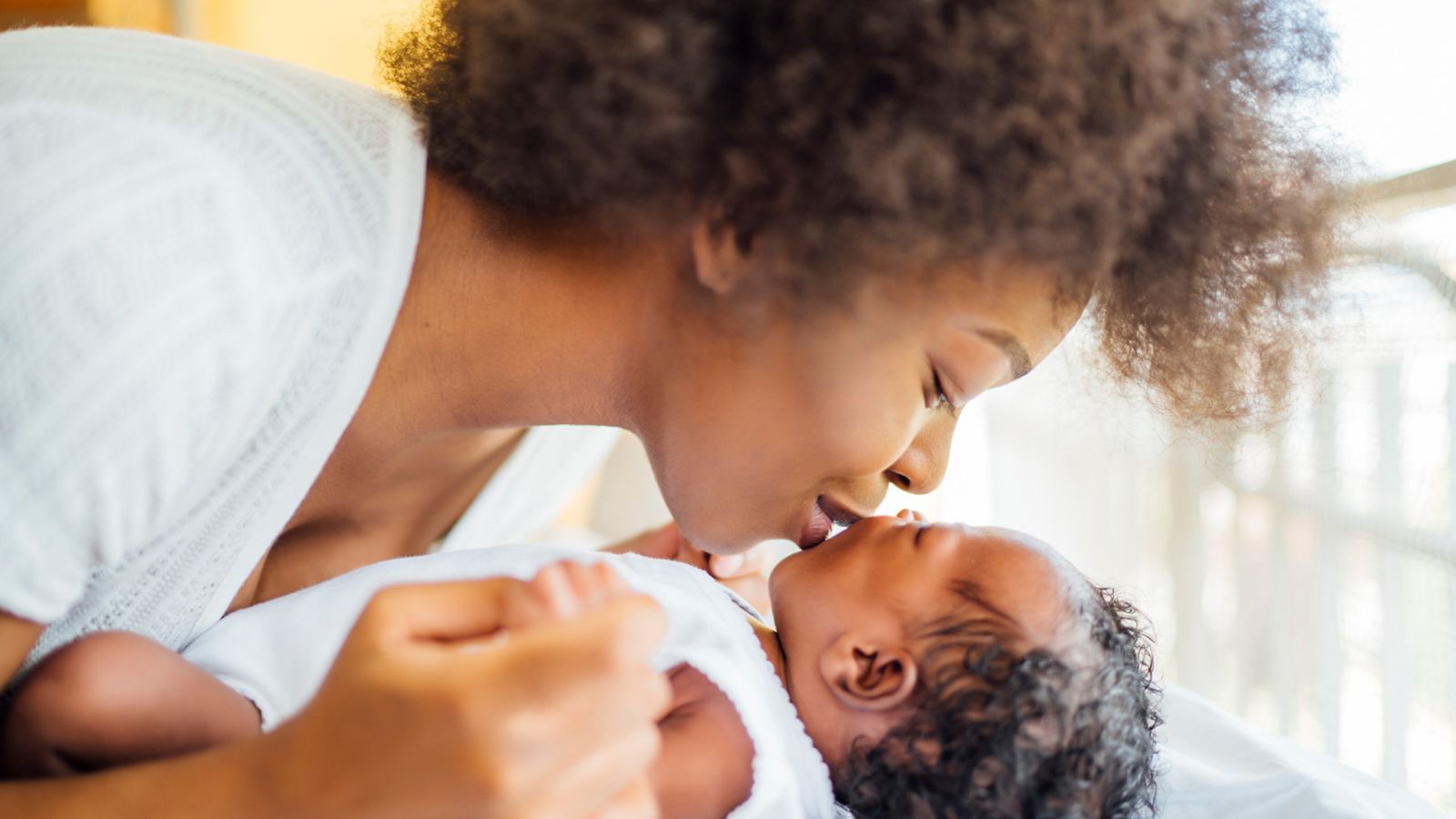 A mother kissing her newborn baby