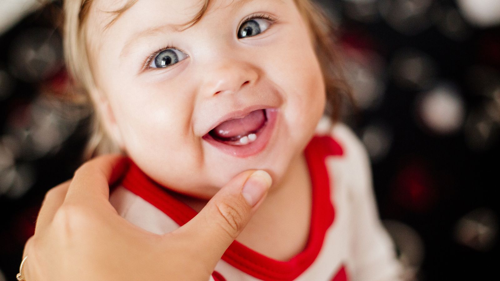 A baby grinning to show off her two little bottom teeth