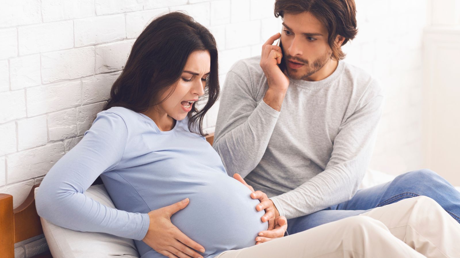A pregnant woman breathing through a contraction while her partner calls on the phone
