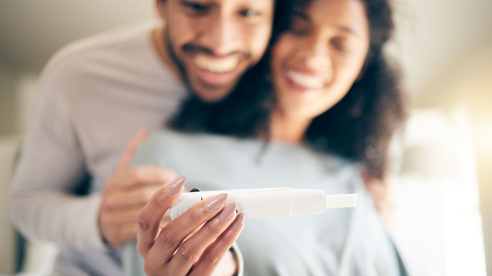 A smiling couple looking at a pregnancy test together