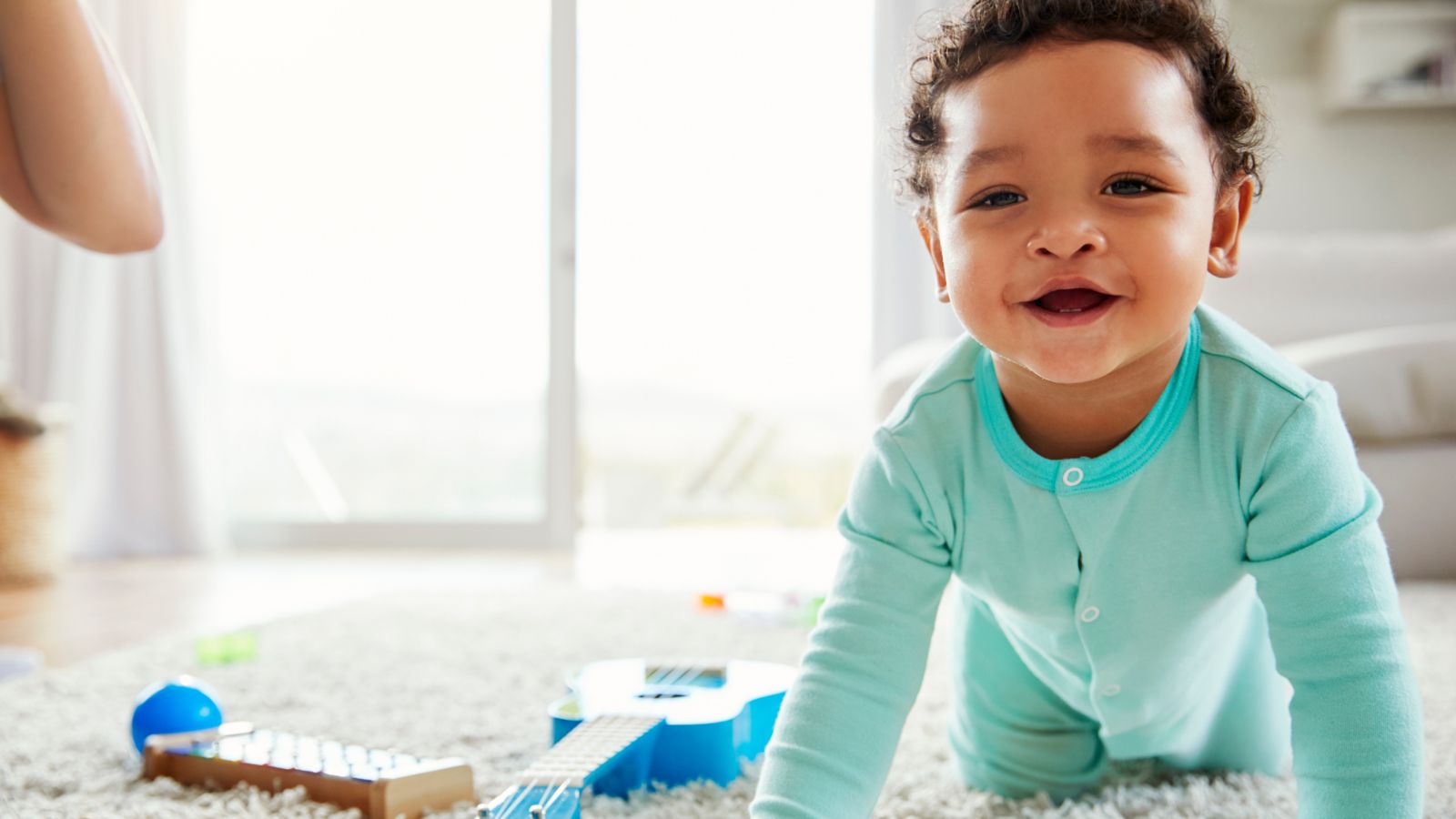A smiling baby crawling on a soft rug