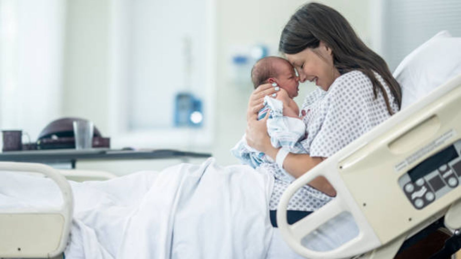 A new mother in her hospital bed touching noses with her newborn