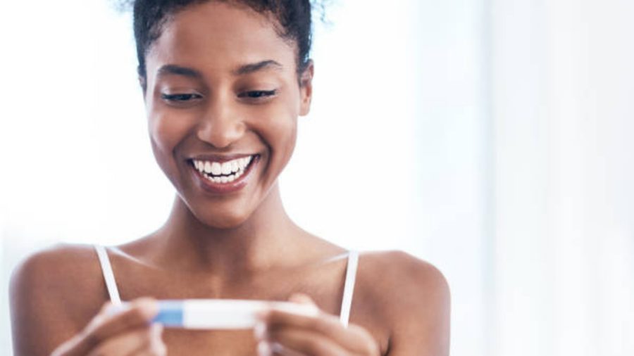 A woman smiling with joy as she looks at a pregnancy test