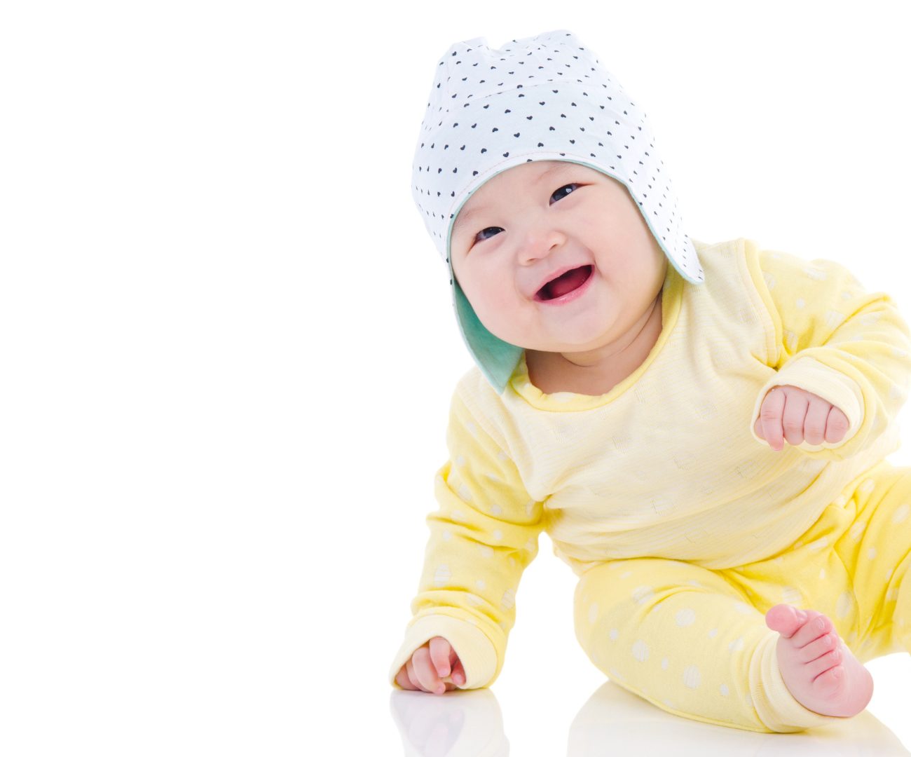 A laughing baby in a yellow outfit sitting up